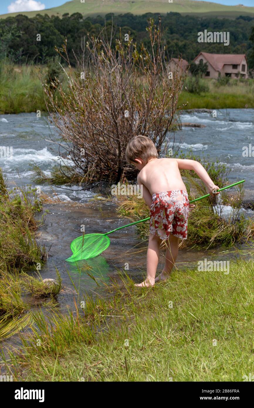 a close up view of a young child that playing in the water with a fishing pole Stock Photo