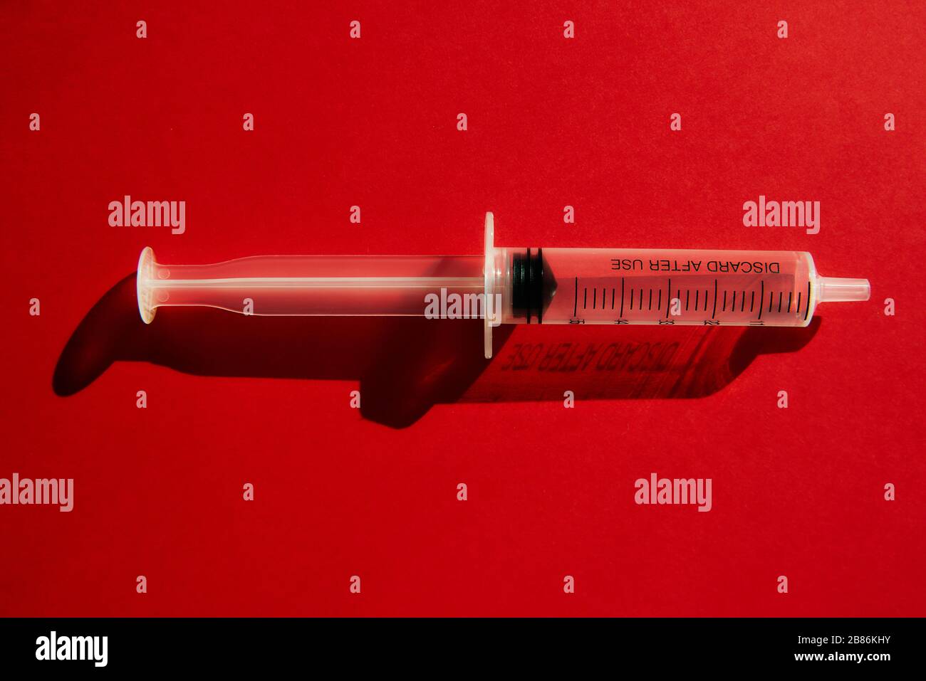 Disposable medical syringe without injection needle on a red background with highlights and shadows. Coronavirus concept. Stop 2019 Novel Coronavirus Stock Photo