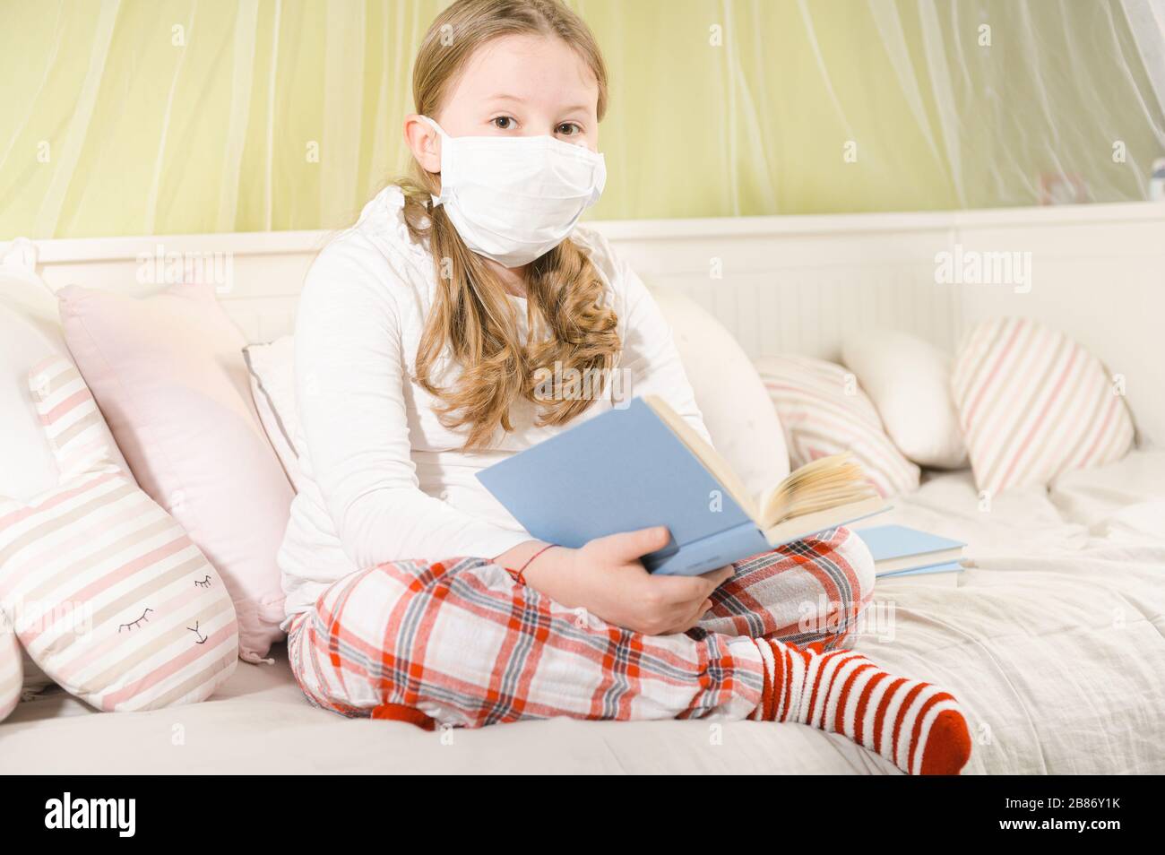 Girl reading a book during quarantine on the bed. Stock Photo