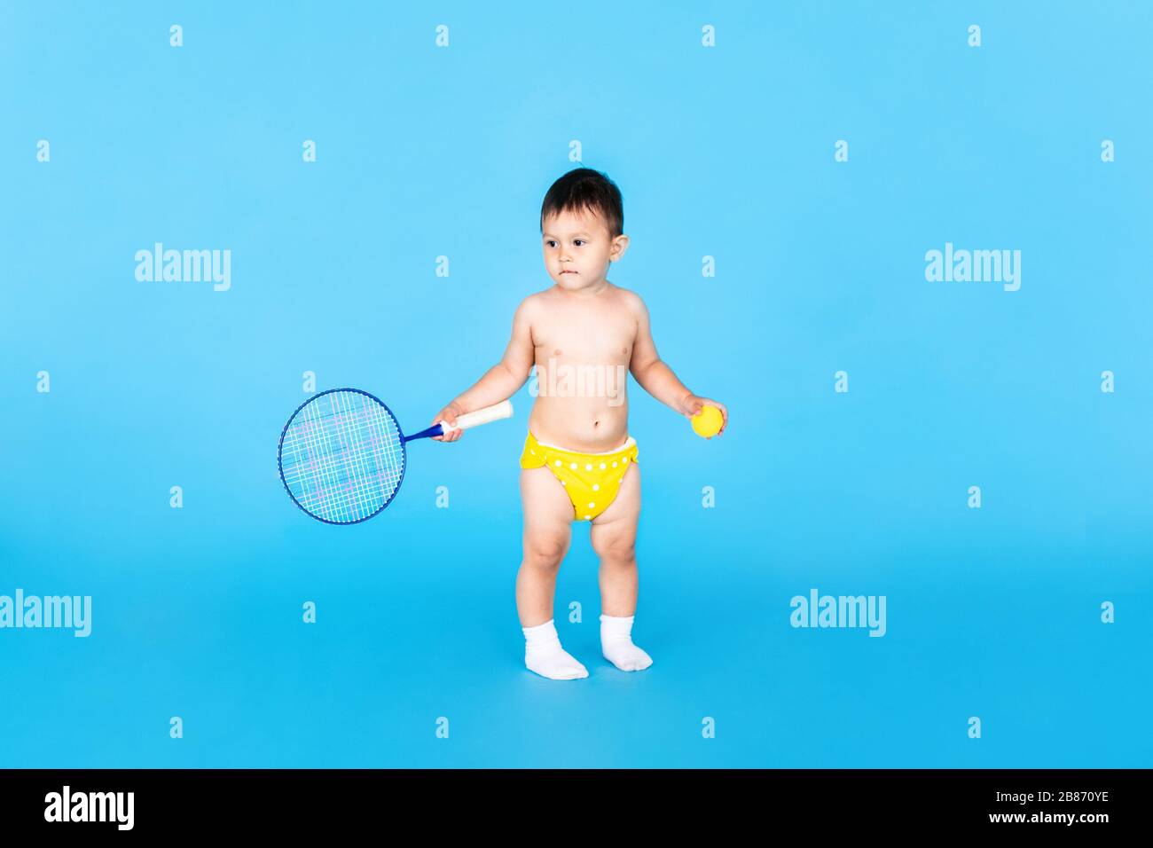 Baby boy jumping and playing badminton on blue background Stock Photo
