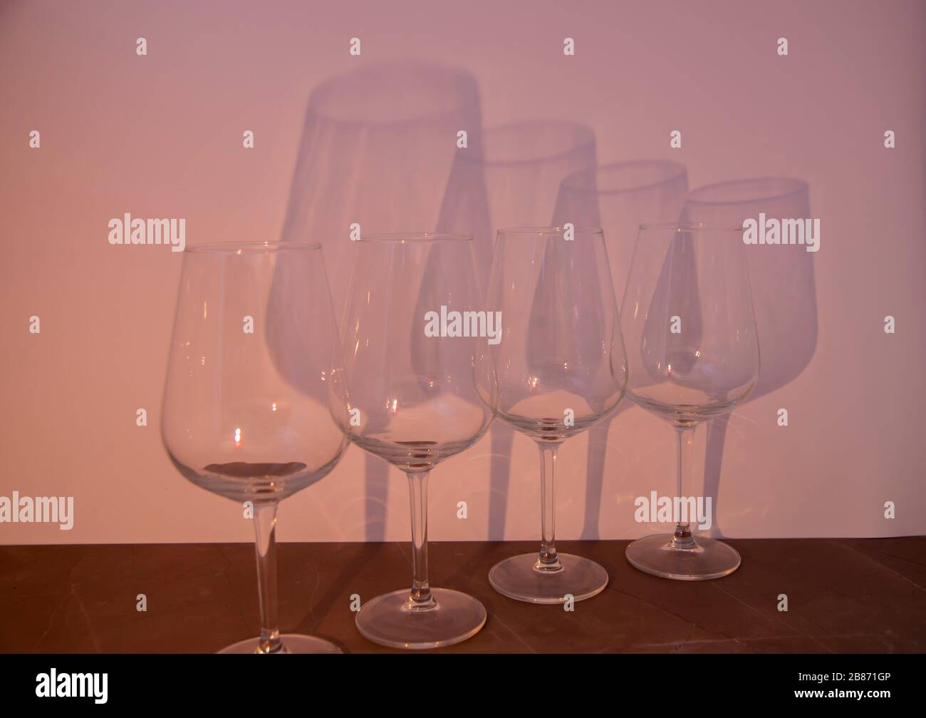 Burning candle in front of glasses, wine glasses behind a candle cast a big shadow in the