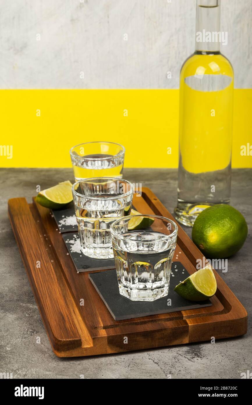 Tequila bottle and shots, limes, salt on wooden board Stock Photo Alamy