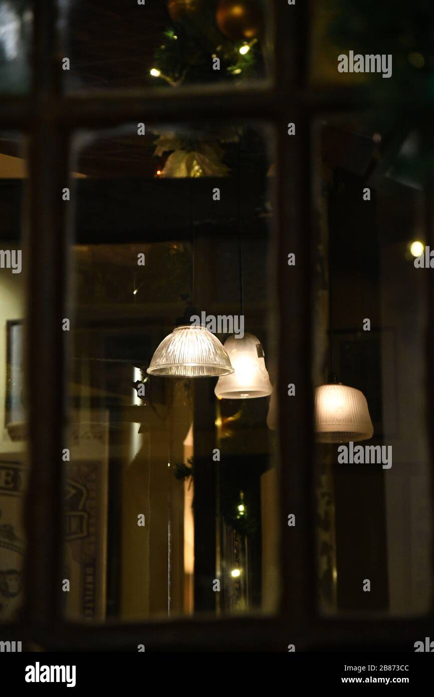 Dark background of abstract reflections in glass window with defocused old wooden frames. Blur reflection of glowing retro lampshades with golden Stock Photo