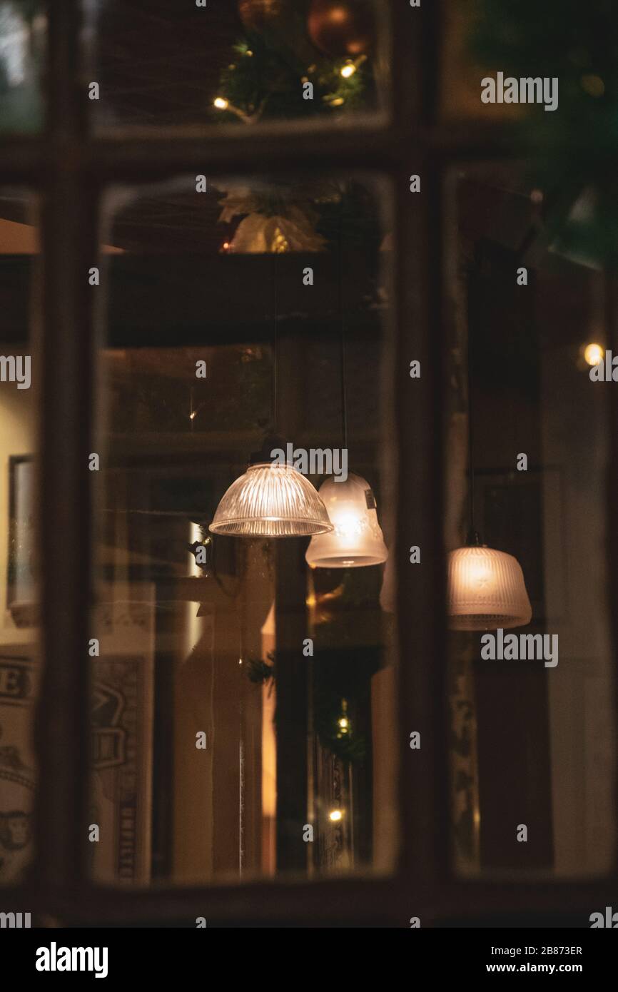 Blurry background of abstract reflections in glass window with defocused old wooden frames. Blur reflection of white retro lampshades with golden even Stock Photo