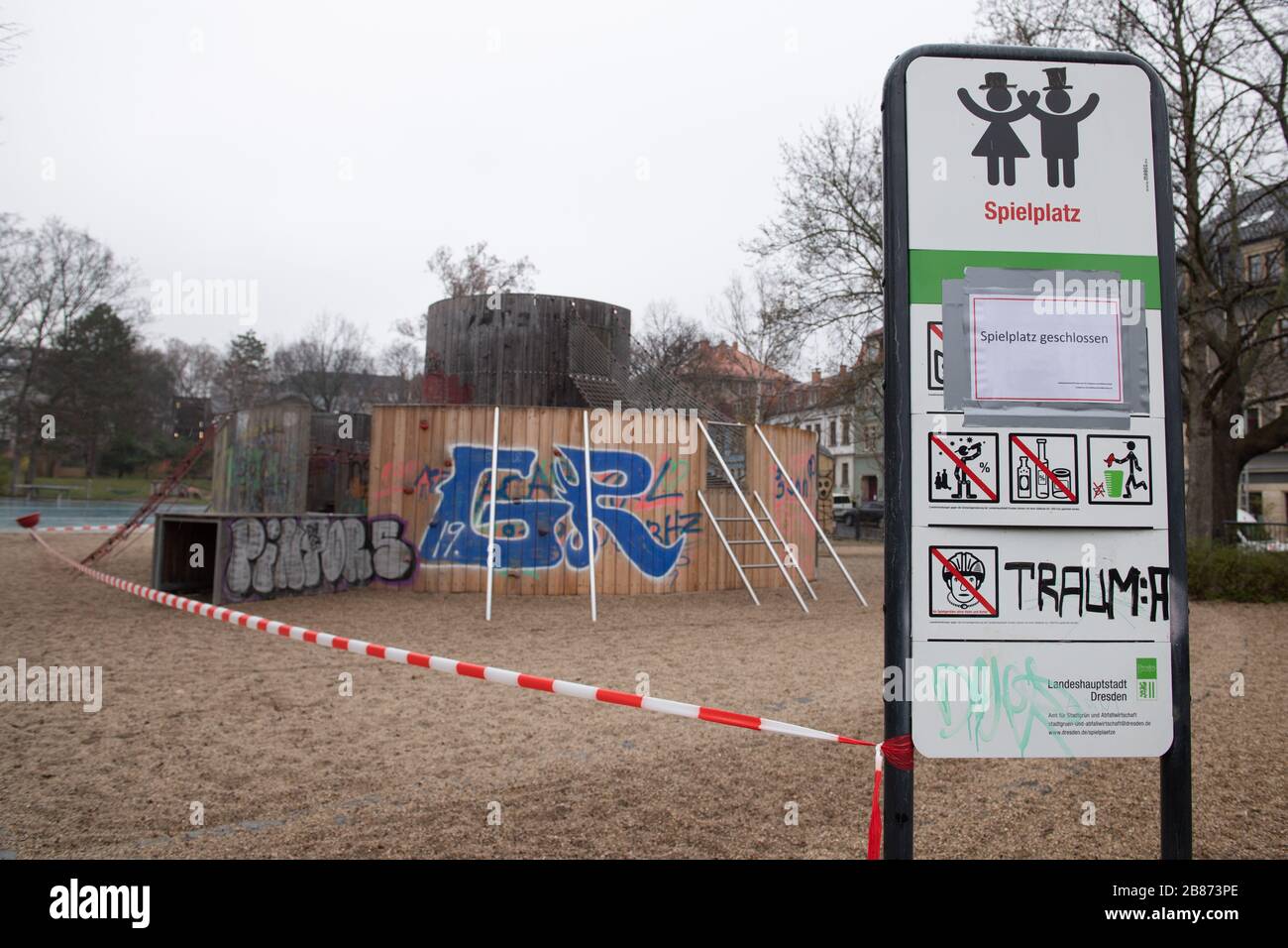 Dresden, Germany. 20th Mar, 2020. A sign with the inscription "Spielplatz geschlossen" (Playground closed) is stuck to a sign on a playground next to a barrier tape. To slow down the spread of the corona virus, the federal government has severely restricted public life. Credit: Sebastian Kahnert/dpa-Zentralbild/dpa/Alamy Live News Stock Photo
