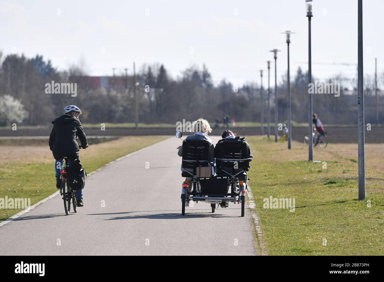 Munich, Deutschland. 18th Mar, 2020. Cyclists ride with a safe distance next to a tandem bicycle, which is occupied by two people, on an asphalt cycle path. ? Sven Simon Fotoagentur GmbH & Co. Press Photo KG # Prinzess-Luise-Str. 41 # 45479 M uelheim/R uhr # Tel. 0208/9413250 # Fax. 0208/9413260 # GLS Bank # BLZ 430 609 67 # Kto. 4030 025 100 # IBAN DE75 4306 0967 4030 0251 00 # BIC GENODEM1GLS # www.svensimon.net. | usage worldwide Credit: dpa/Alamy Live News Stock Photo
