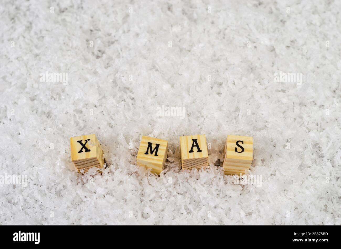 x mas word made of letters on wooden cubes on a snow background 2 Stock Photo