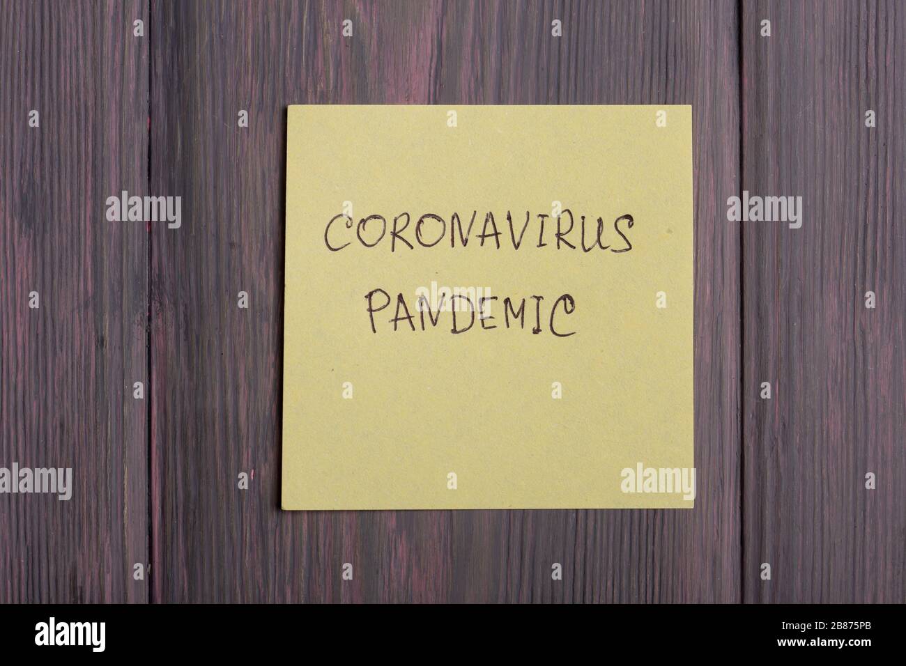 Text Coronavirus Pandemic on sticky note on wooden background - healthcare and medical concept Stock Photo