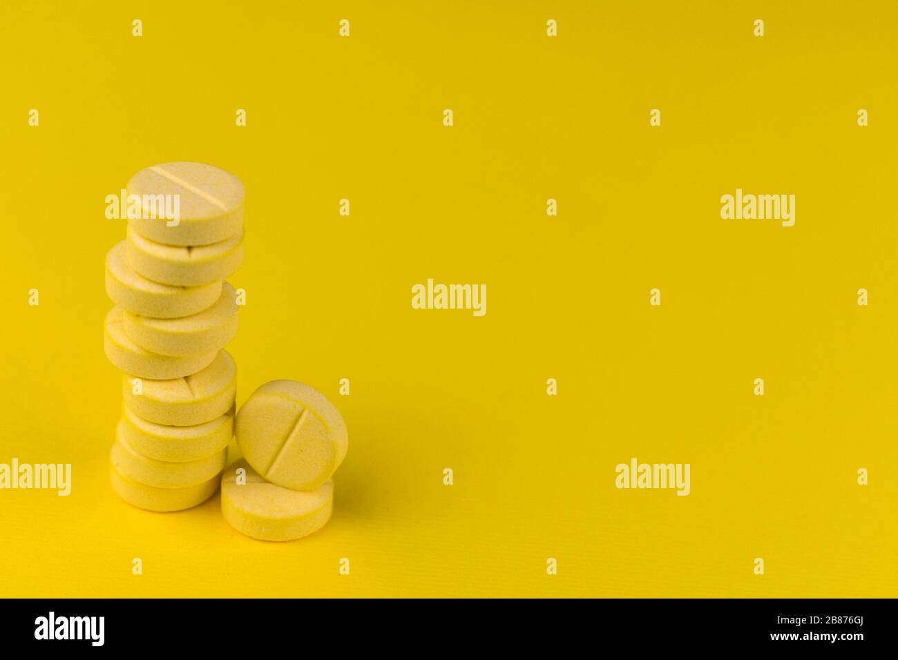 Vitamin C tablets in a stack on a yellow background. Copy space Stock