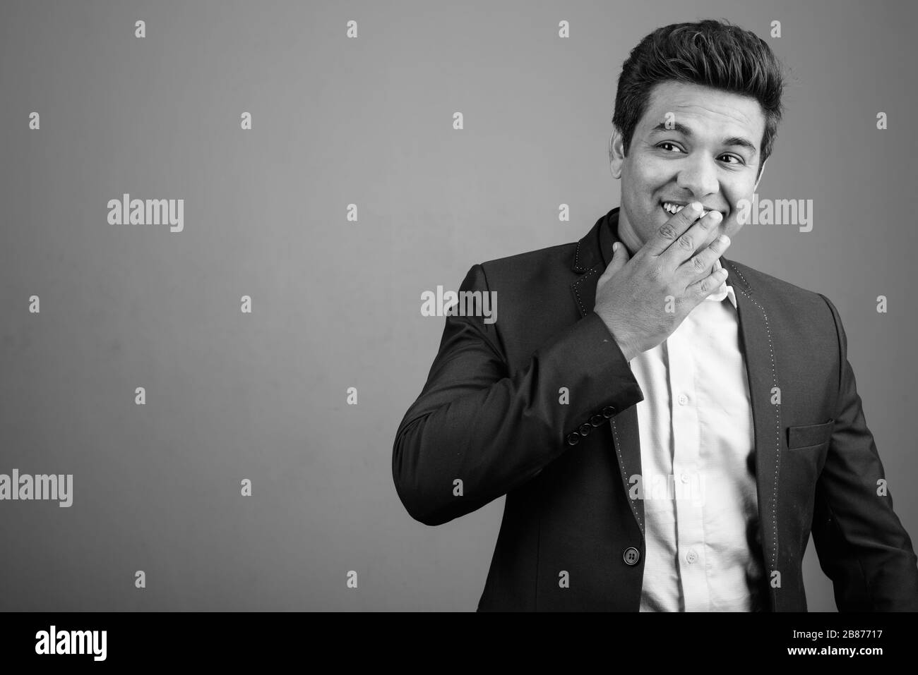 Indian businessman wearing suit against gray background Stock Photo - Alamy