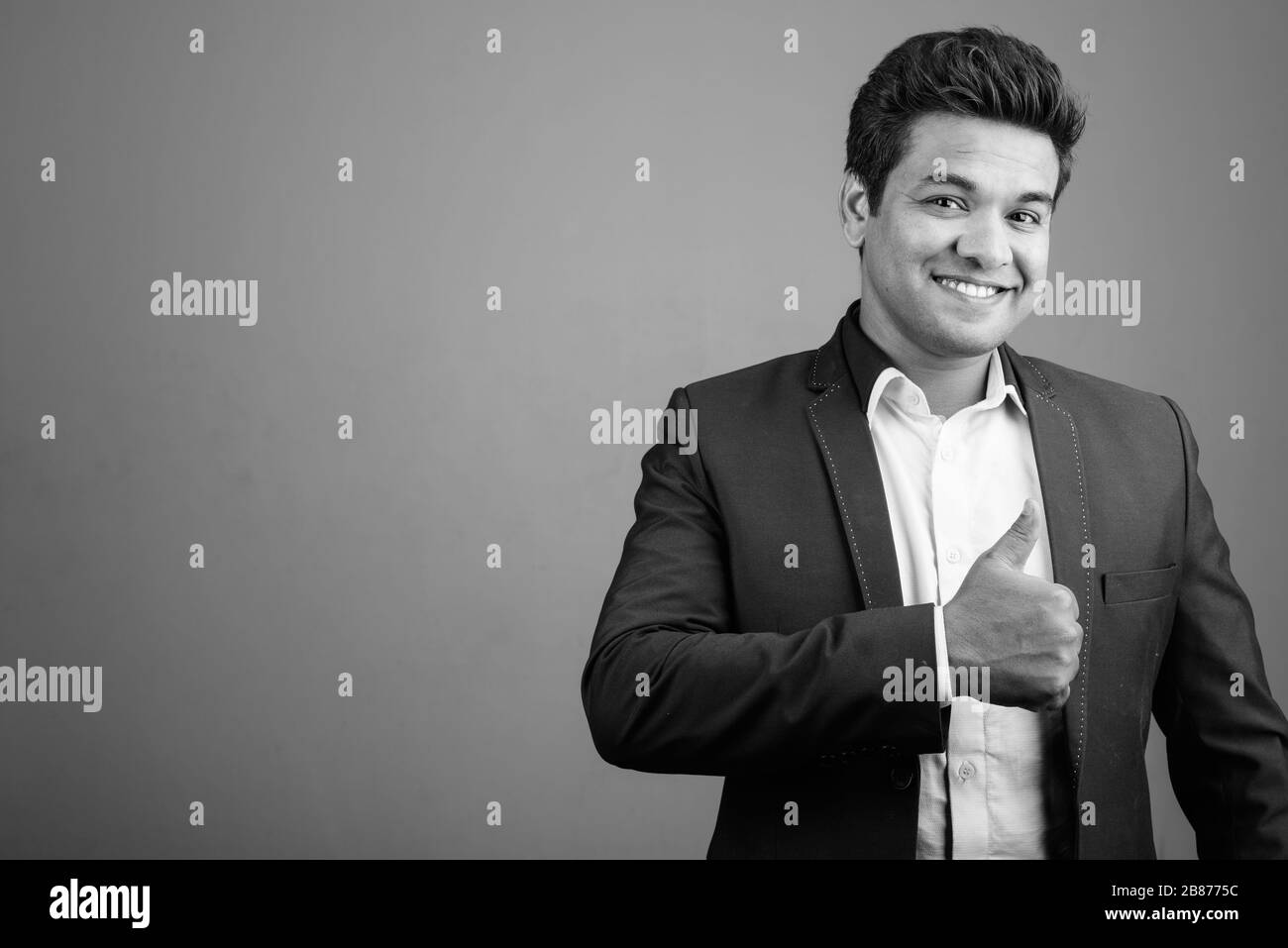 Indian businessman wearing suit against gray background Stock Photo - Alamy
