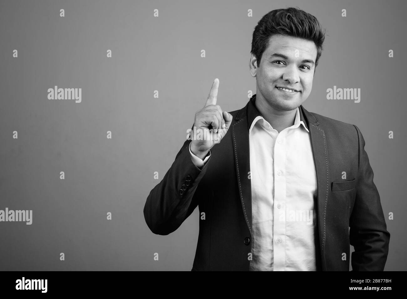 Indian businessman wearing suit against gray background Stock Photo - Alamy