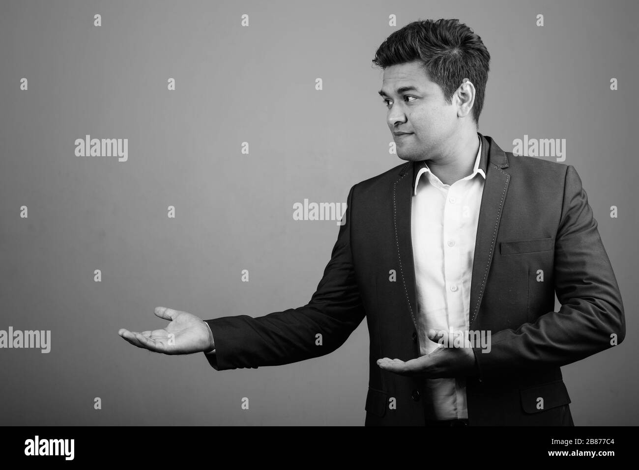 Indian businessman wearing suit against gray background Stock Photo - Alamy