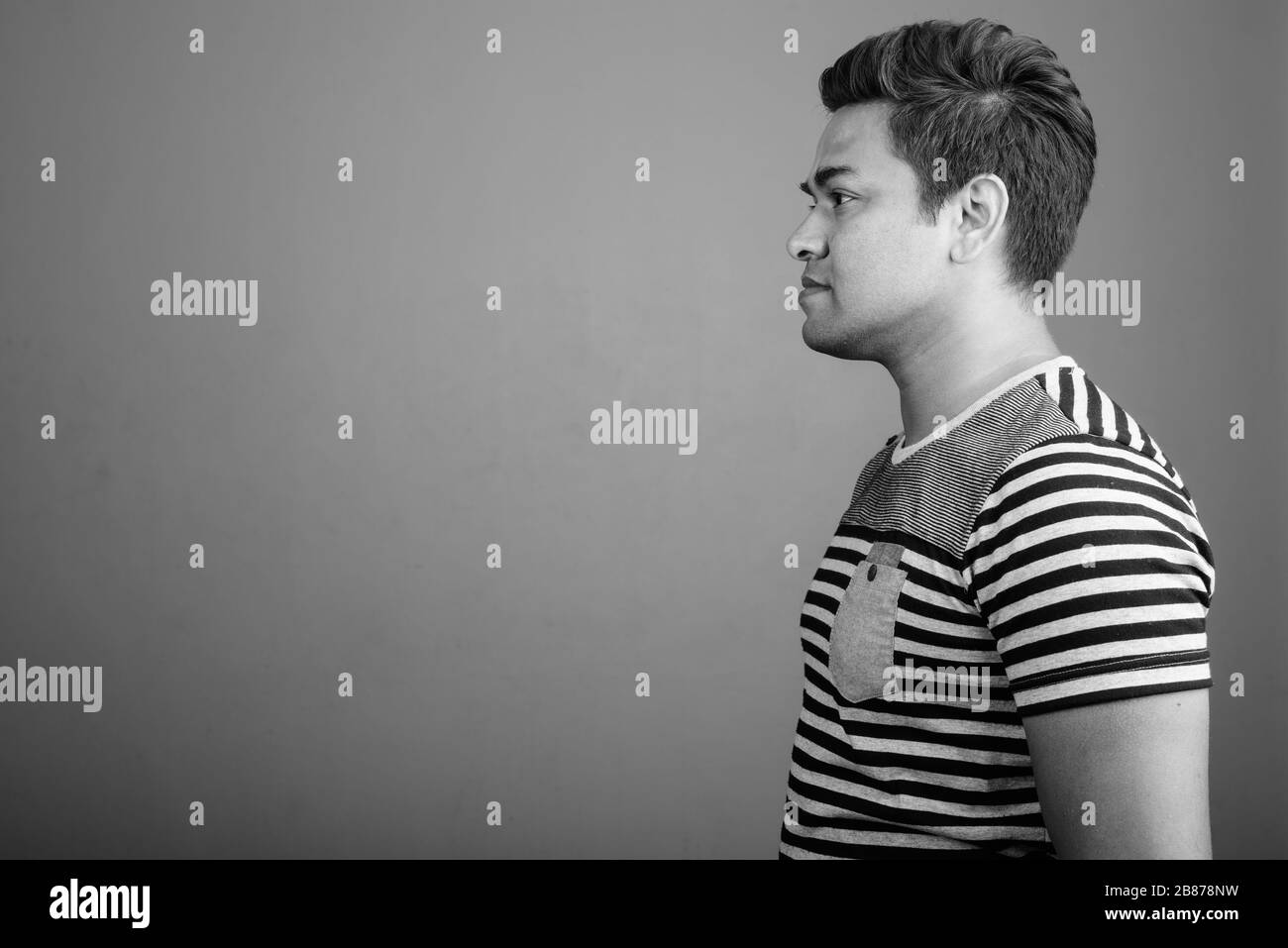 Indian man wearing striped shirt against gray background Stock Photo