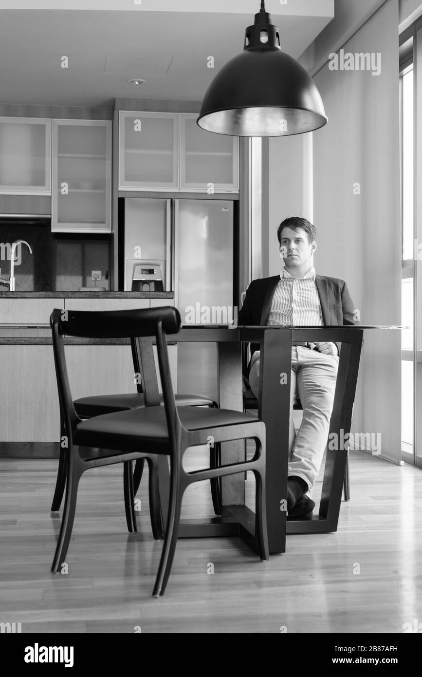 Young handsome businessman sitting in the dining room near the kitchen Stock Photo