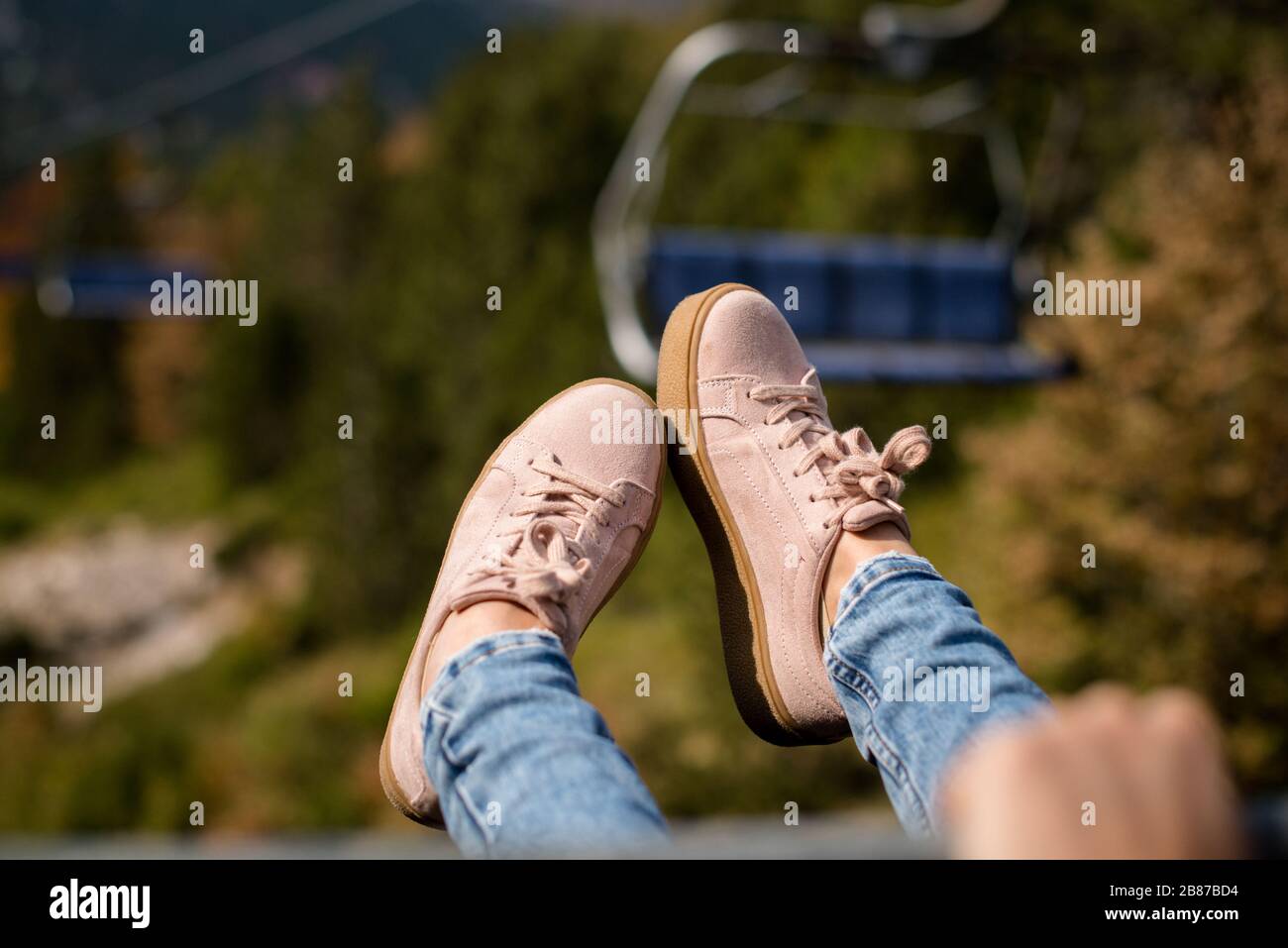 chairlift ride view with pink sneakers Stock Photo
