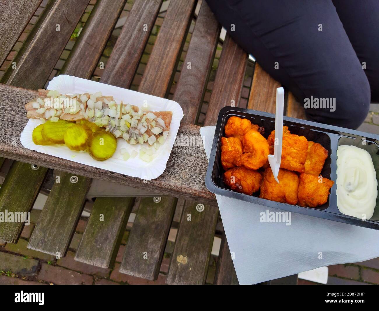 snack on a Dutch wooden bench with fresh herring with onions and