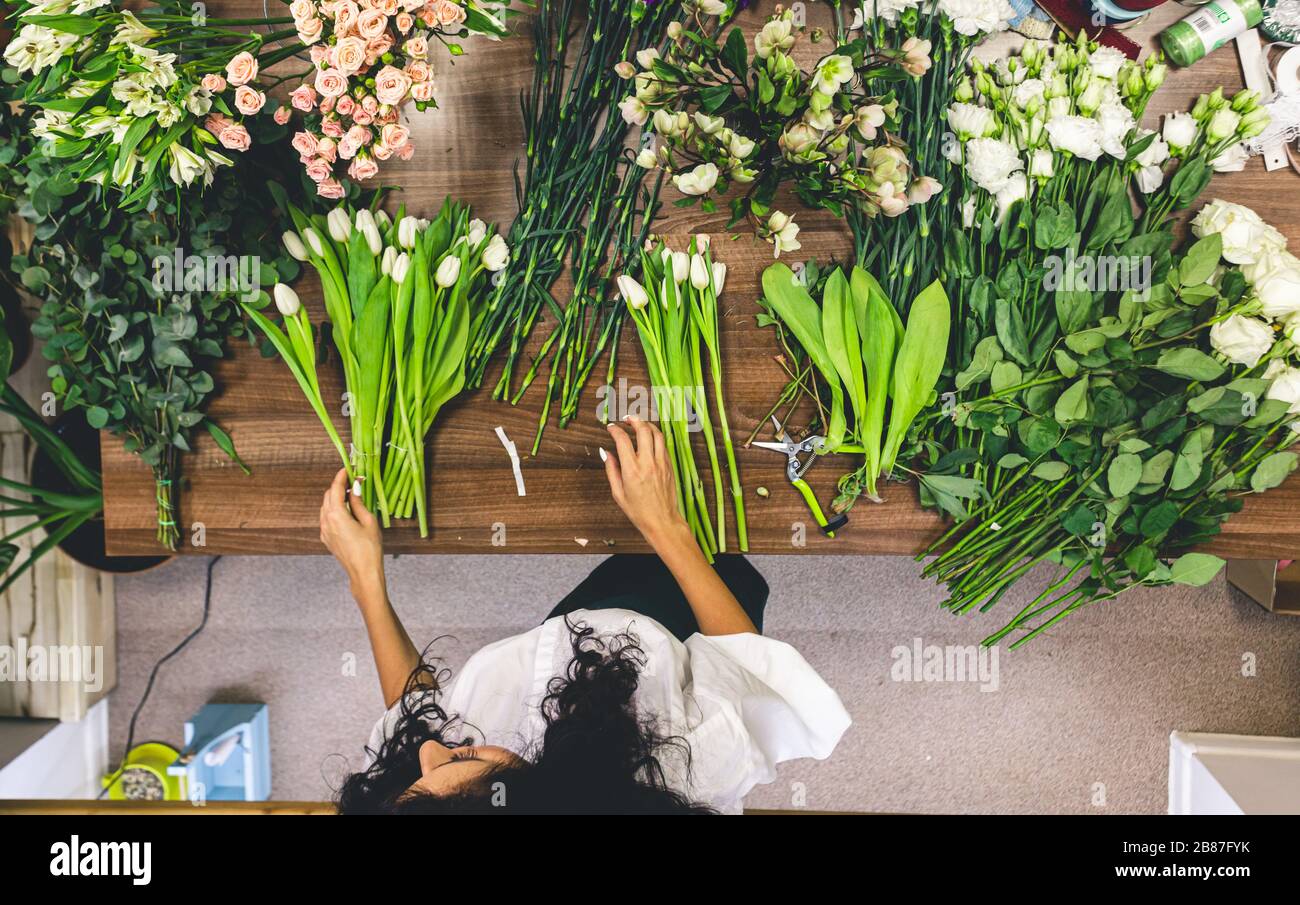 Attractive young woman florist is working in a flower shop Stock Photo ...