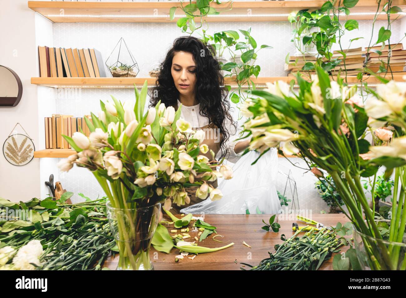Attractive young woman florist is working in a flower shop Stock Photo ...