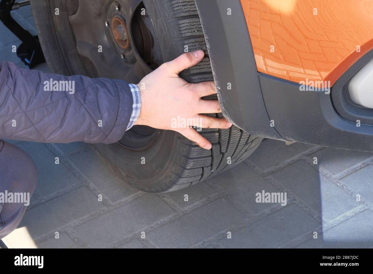 Driver changing a wheel of modern car. Damaged car tyre. Wheel balancing or repair and change