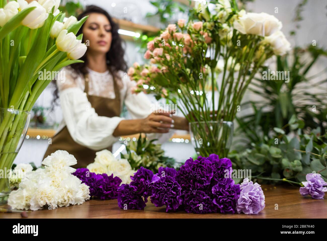 Attractive young woman florist is working in a flower shop Stock Photo ...