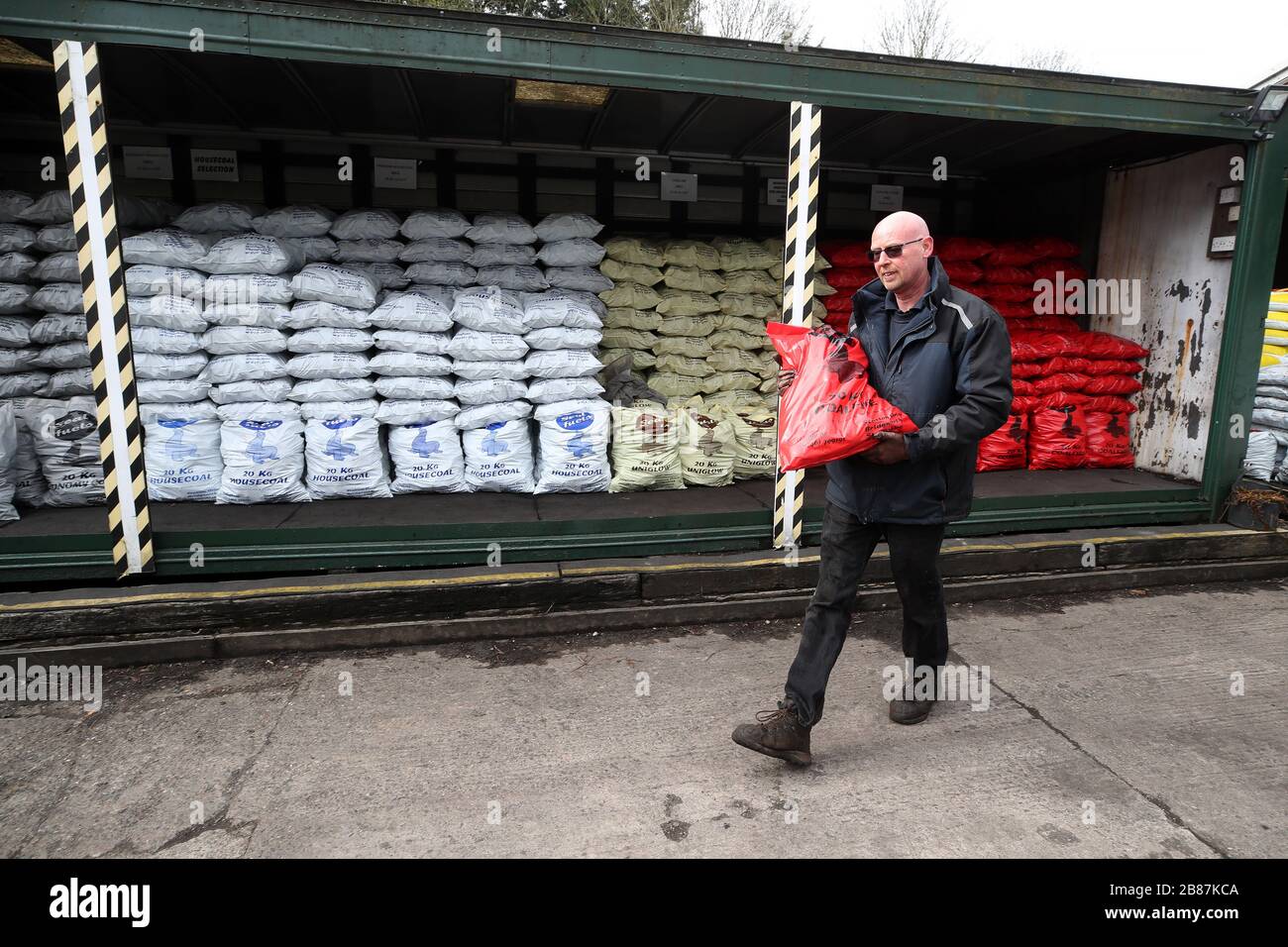 A man carrying a bag of coal at Seal Fuels in Bridgnorth, Shropshire, as the UK's coronavirus death toll reached 144 as of 1pm on Thursday, with around four in 10 of all deaths so far in London. Stock Photo