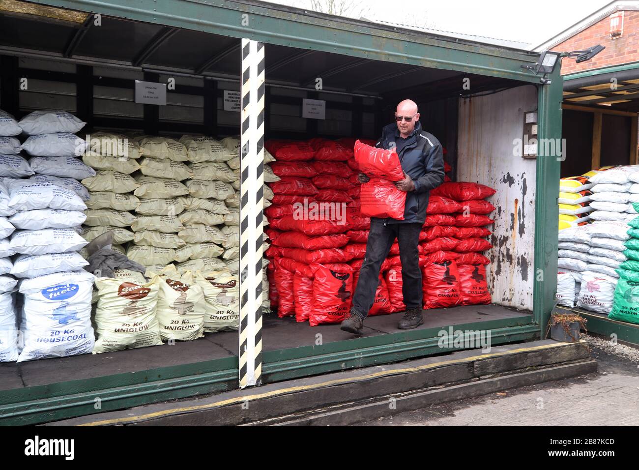 A man carrying a bag of coal at Seal Fuels in Bridgnorth, Shropshire, as the UK's coronavirus death toll reached 144 as of 1pm on Thursday, with around four in 10 of all deaths so far in London. Stock Photo