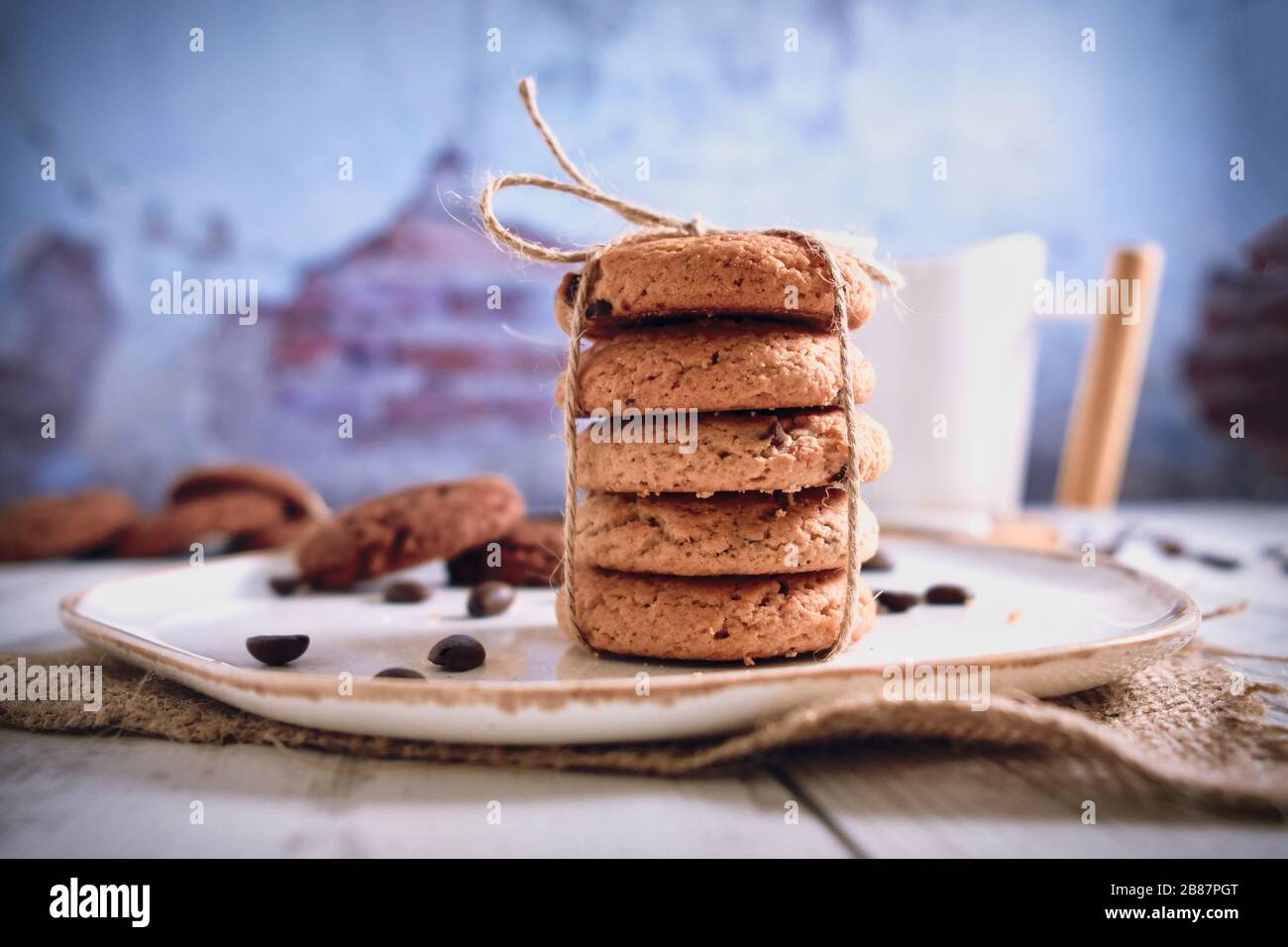 Roasted brown coffee beans and Hot coffee. Beautifully stacked cookies with chocolate on Wooden table. Chocolate chip cookies Vintage Color. Stock Photo