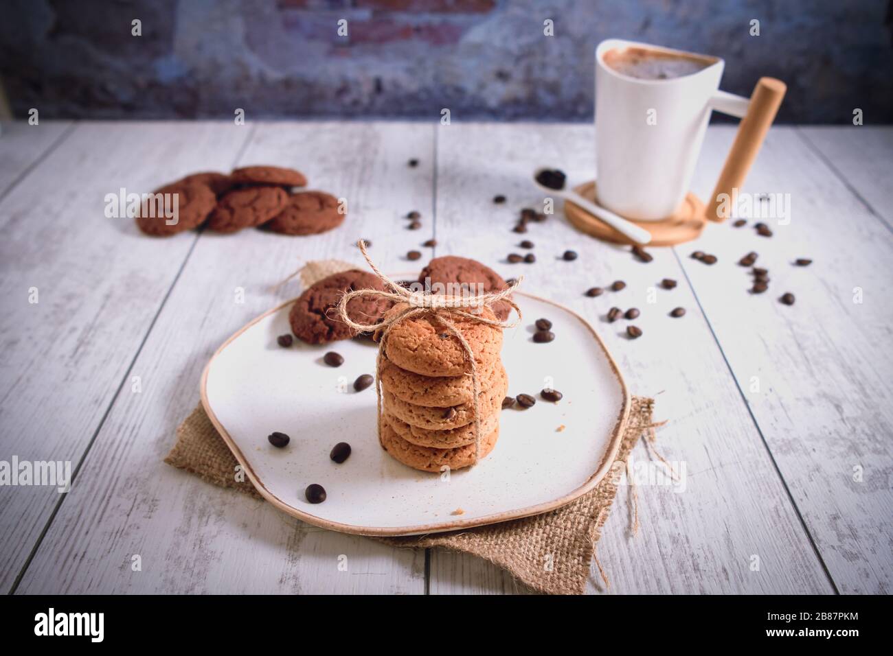 Roasted brown coffee beans and Hot coffee. Beautifully stacked cookies with chocolate on Wooden table. Chocolate chip cookies Vintage Color. Stock Photo