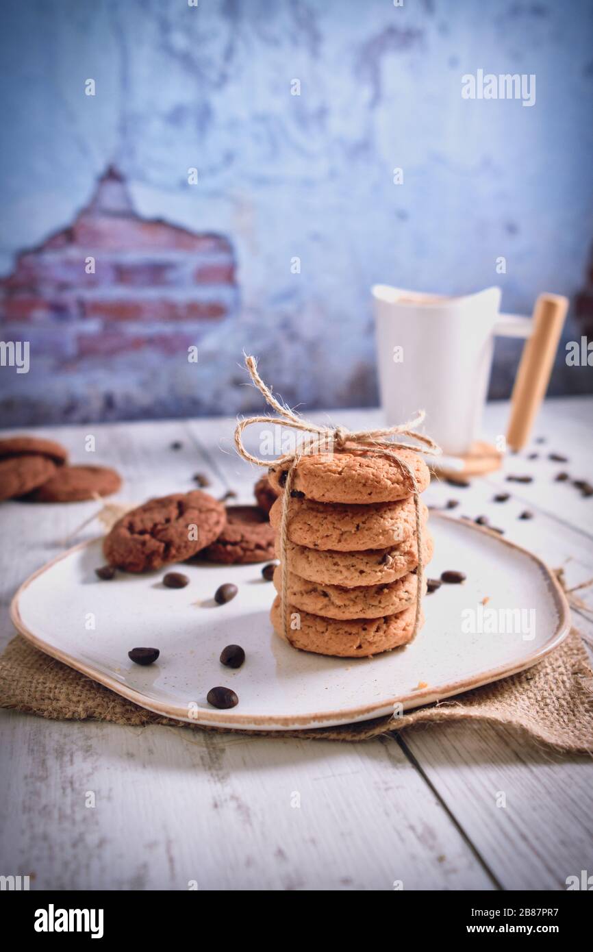 Roasted brown coffee beans and Hot coffee. Beautifully stacked cookies with chocolate on Wooden table. Chocolate chip cookies Vintage Color. Stock Photo