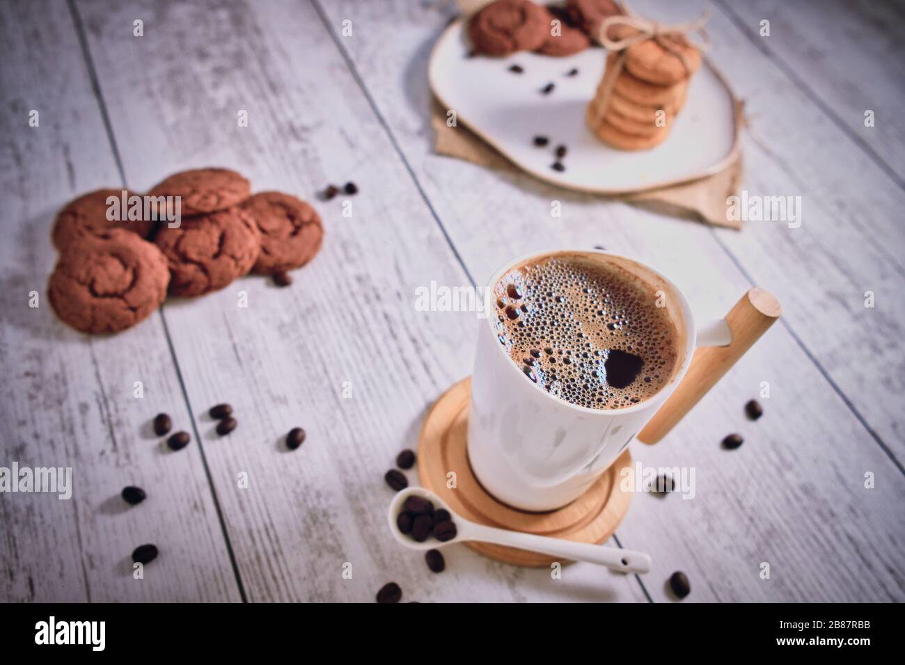 Roasted brown coffee beans and Hot coffee. Beautifully stacked cookies with chocolate on Wooden table. Chocolate chip cookies Vintage Color. Stock Photo