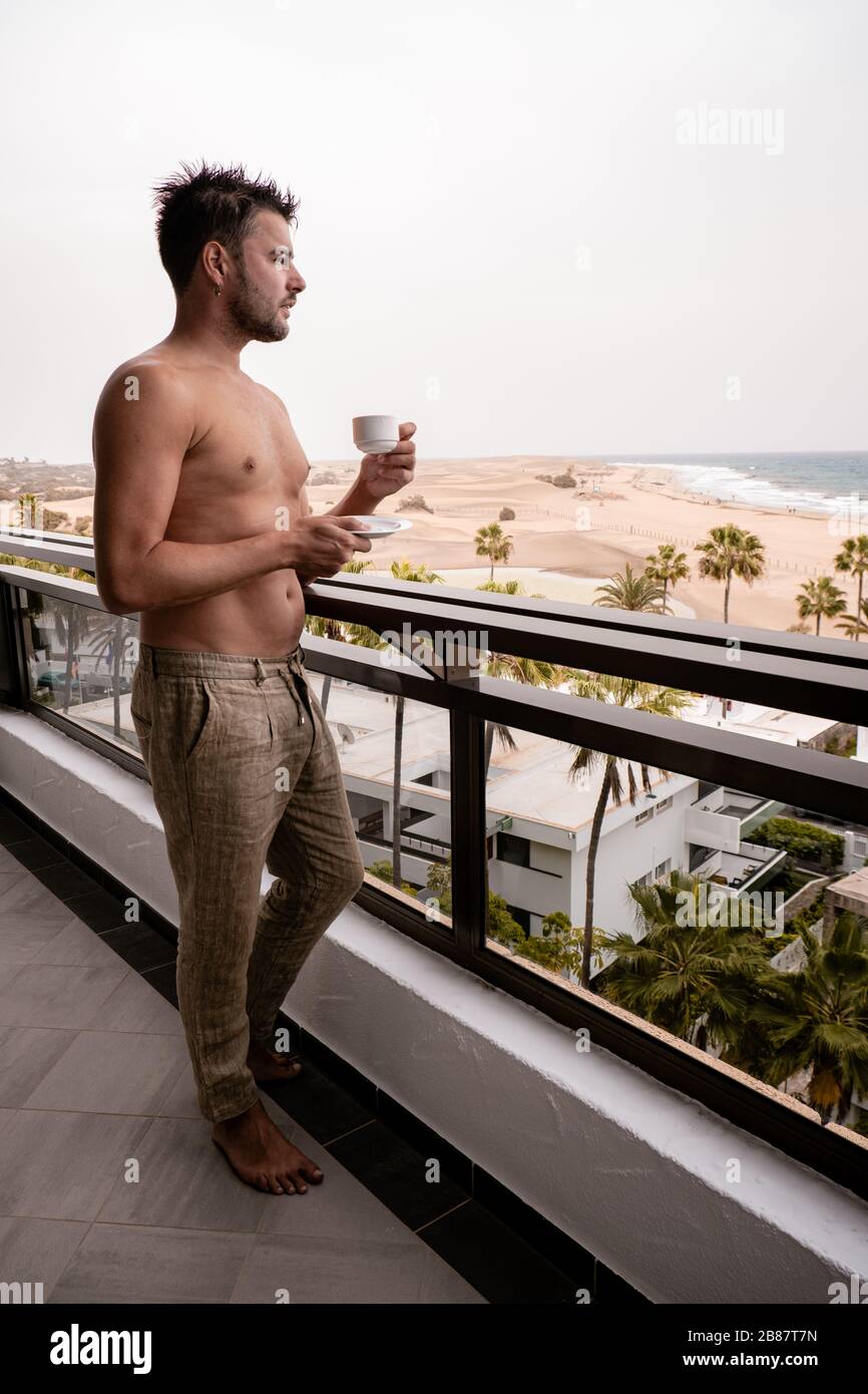 Maspalomas Gran Canaria young men in bathrobe drinking coffee on the balcony in the morning on vacation Stock Photo