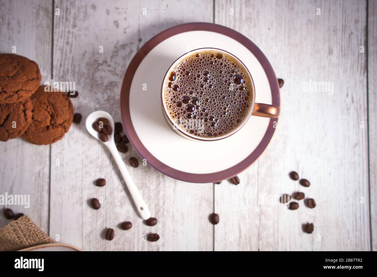 Roasted brown coffee beans and Hot coffee. Beautifully stacked cookies with chocolate on Wooden table. Chocolate chip cookies Vintage Color. Stock Photo