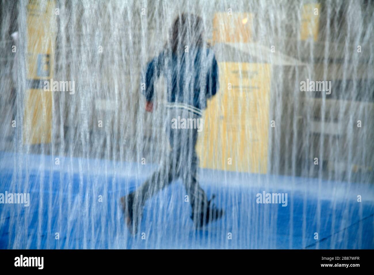 Young boy plays and runs in water fountain installation South Bank London Stock Photo