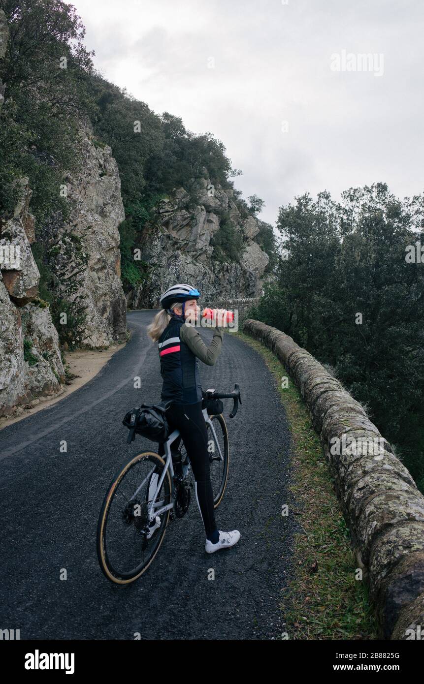 Female cyclist resting on long climb drinking some water Stock Photo