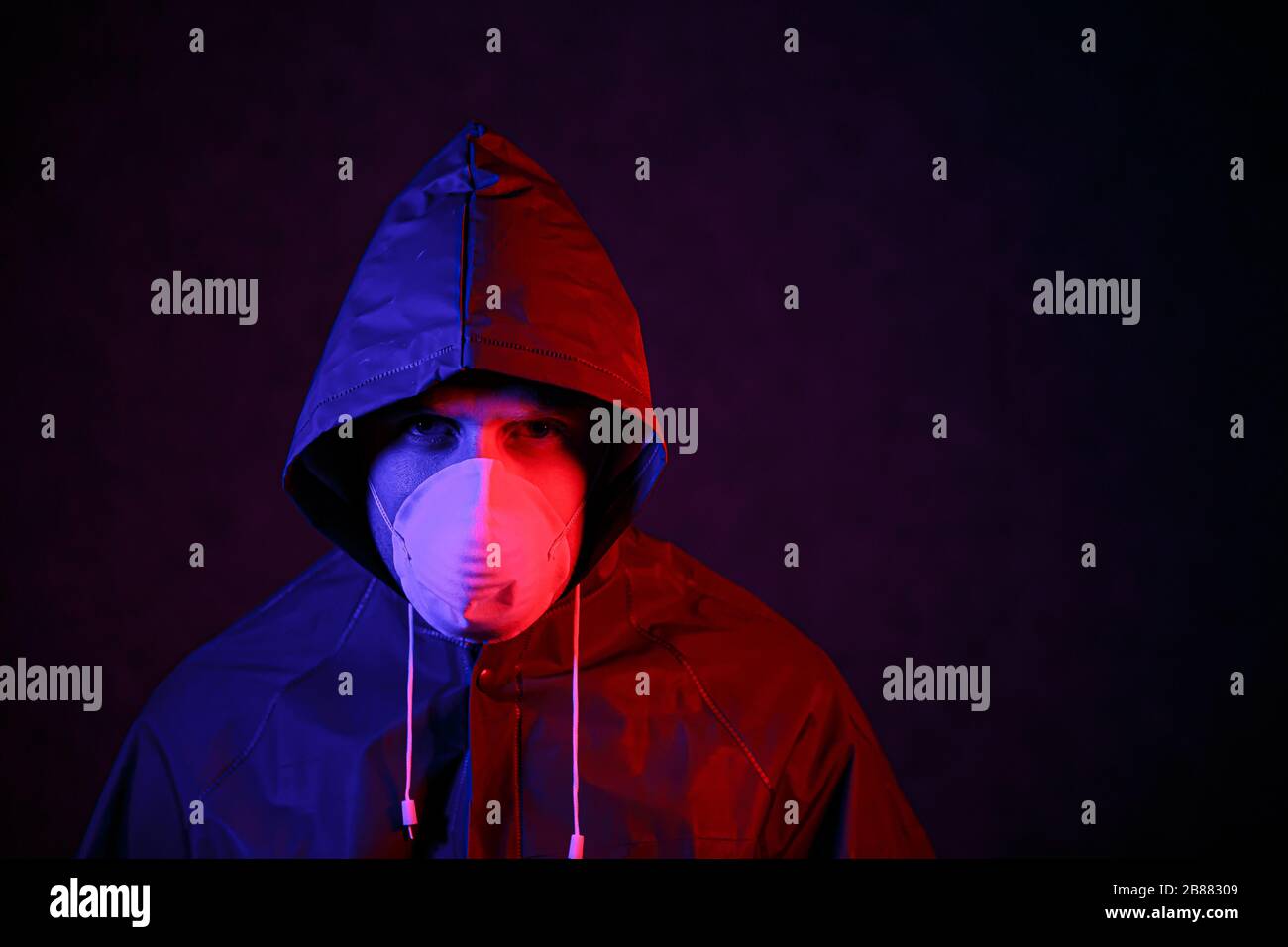 Coronavirus. A man in a mask and chemical protection suit in red and blue light. Fight against the virus Stock Photo