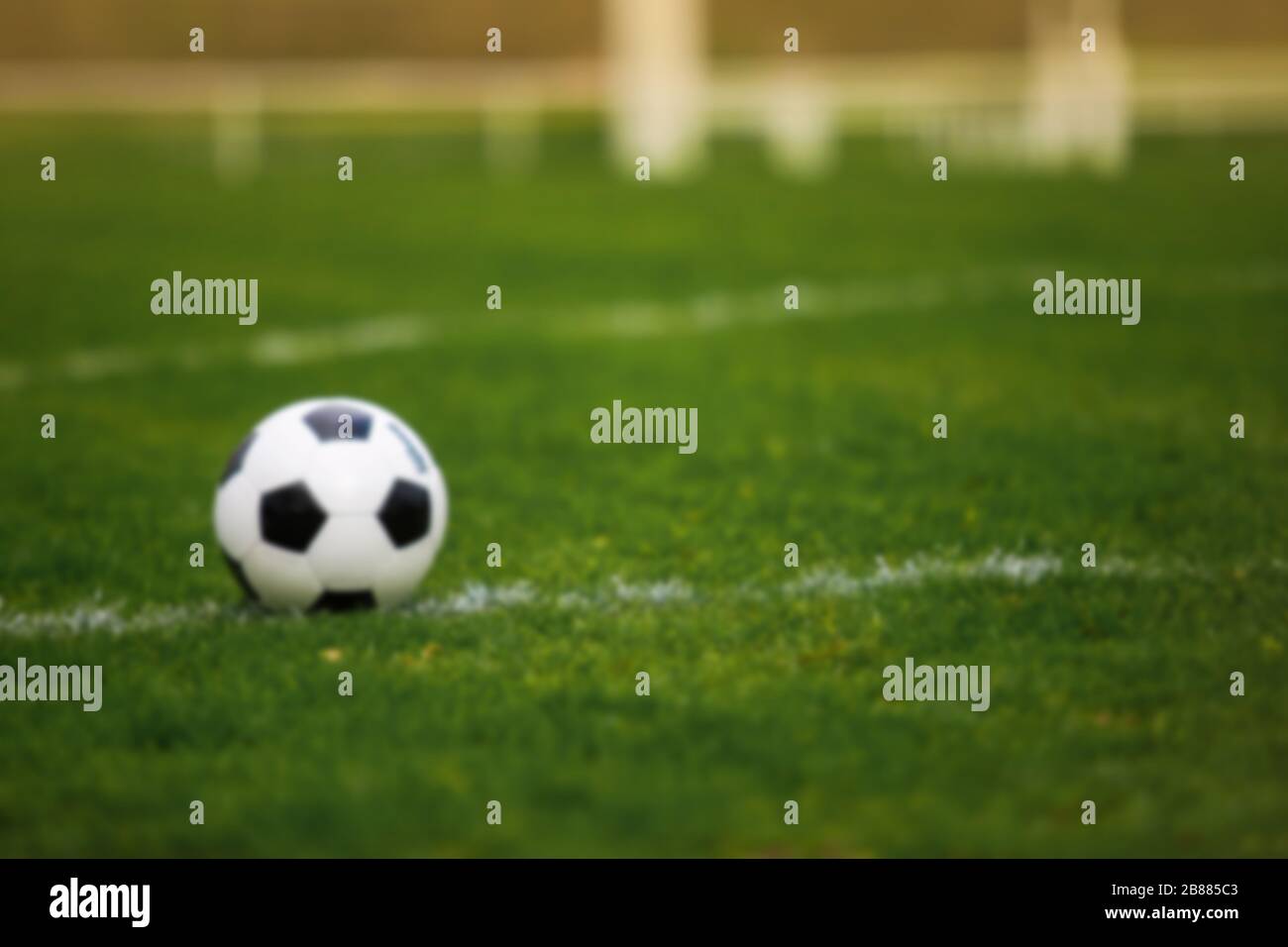 Blurred background of a Classic soccer ball, typical black and white pattern, placed on the white marking line of the stadium turf. Traditional footba Stock Photo
