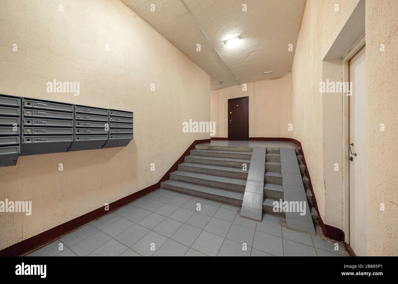 Entrance hallway of an apartment building with mailboxes staircase and wheelchair ramp Stock Photo