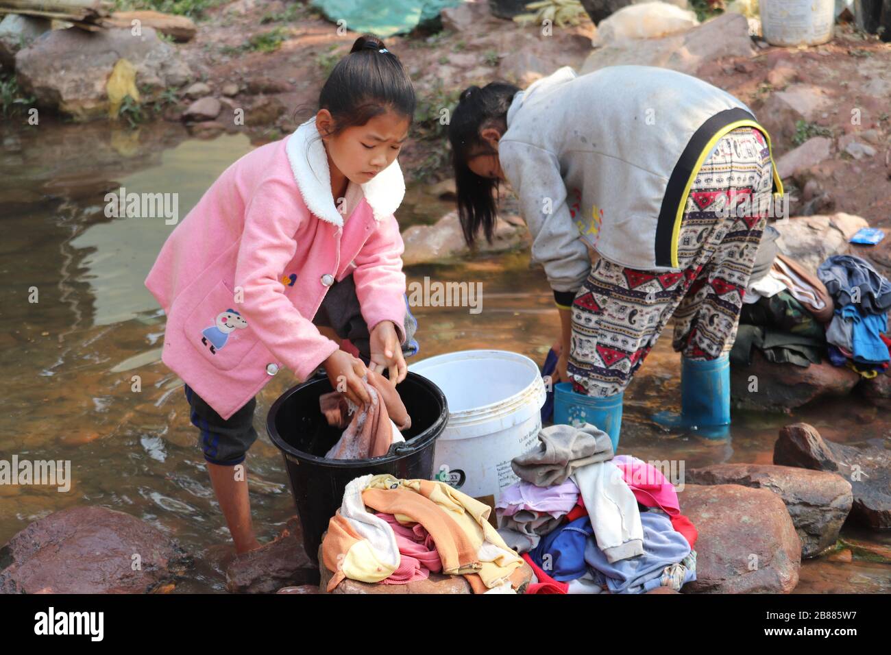 TRIBAL WOMEN WASHING THEIR CLOTHES IN A VILLAGE IN LUANG NAMTHA,NORTHERN LAOS. Stock Photo