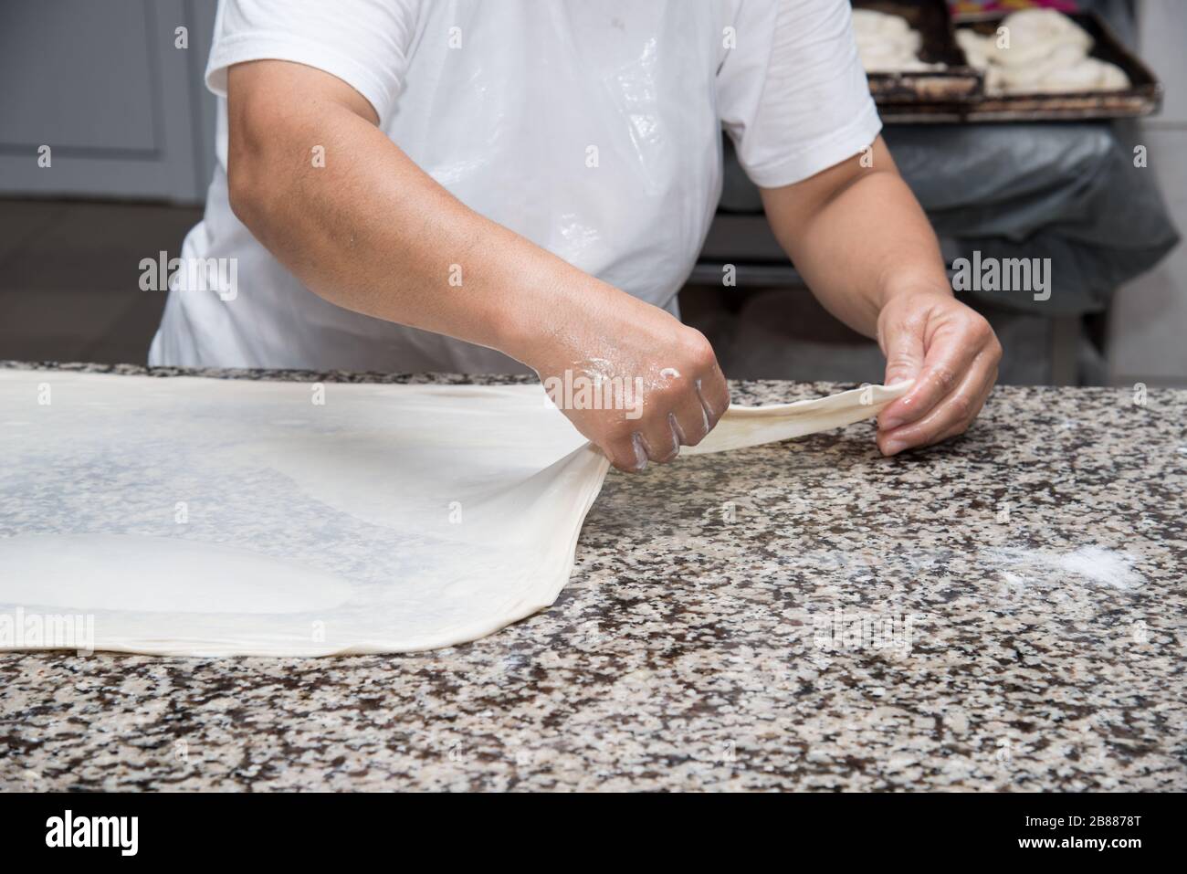 close up of female hands kneading dough and making banitsa - typical ...