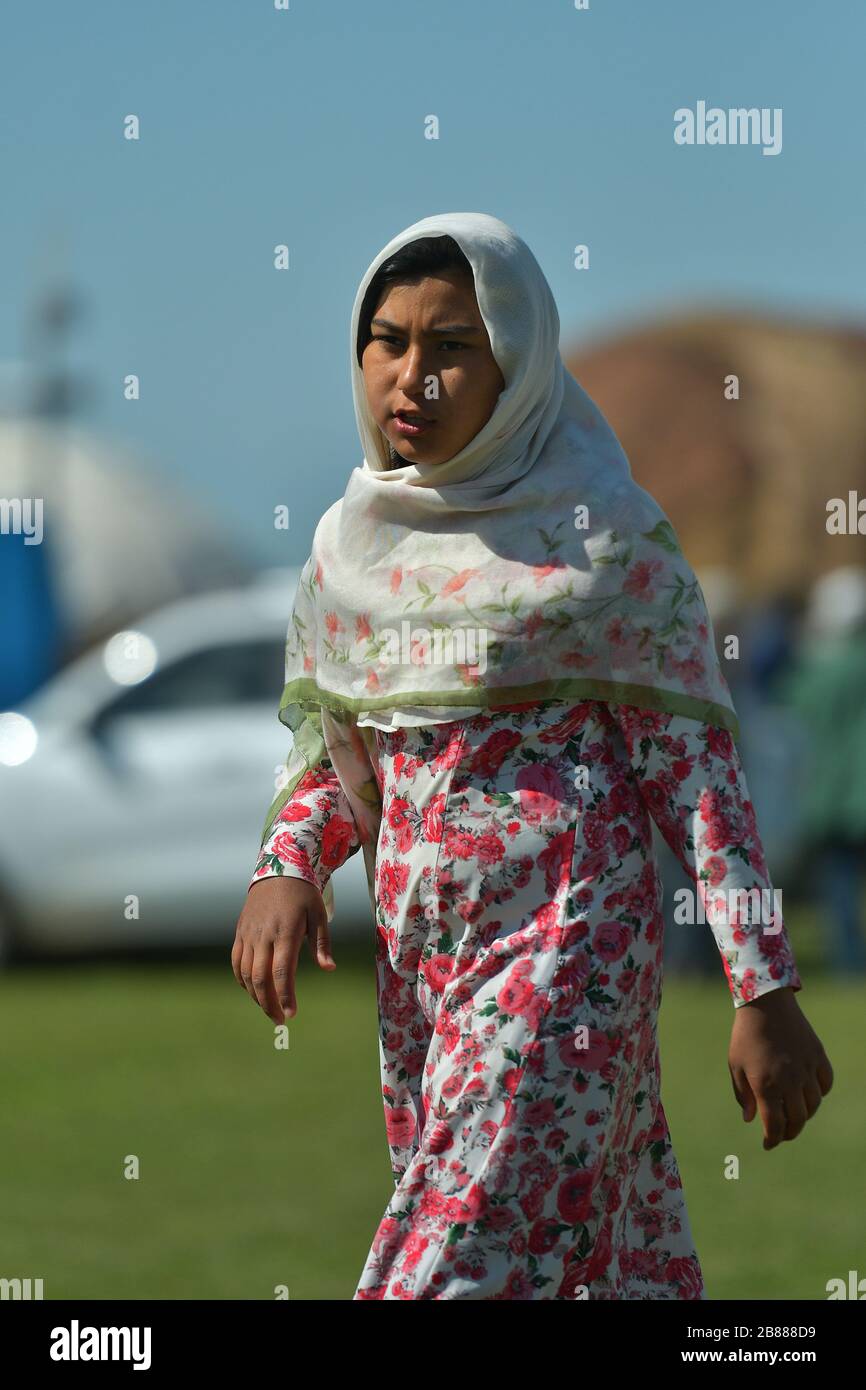 TURKMENISTAN, ASHGABAT - MAY 1, 2019: Day of turkmen racehorse. Public. Girl in a traditional clothes walking by. Stock Photo