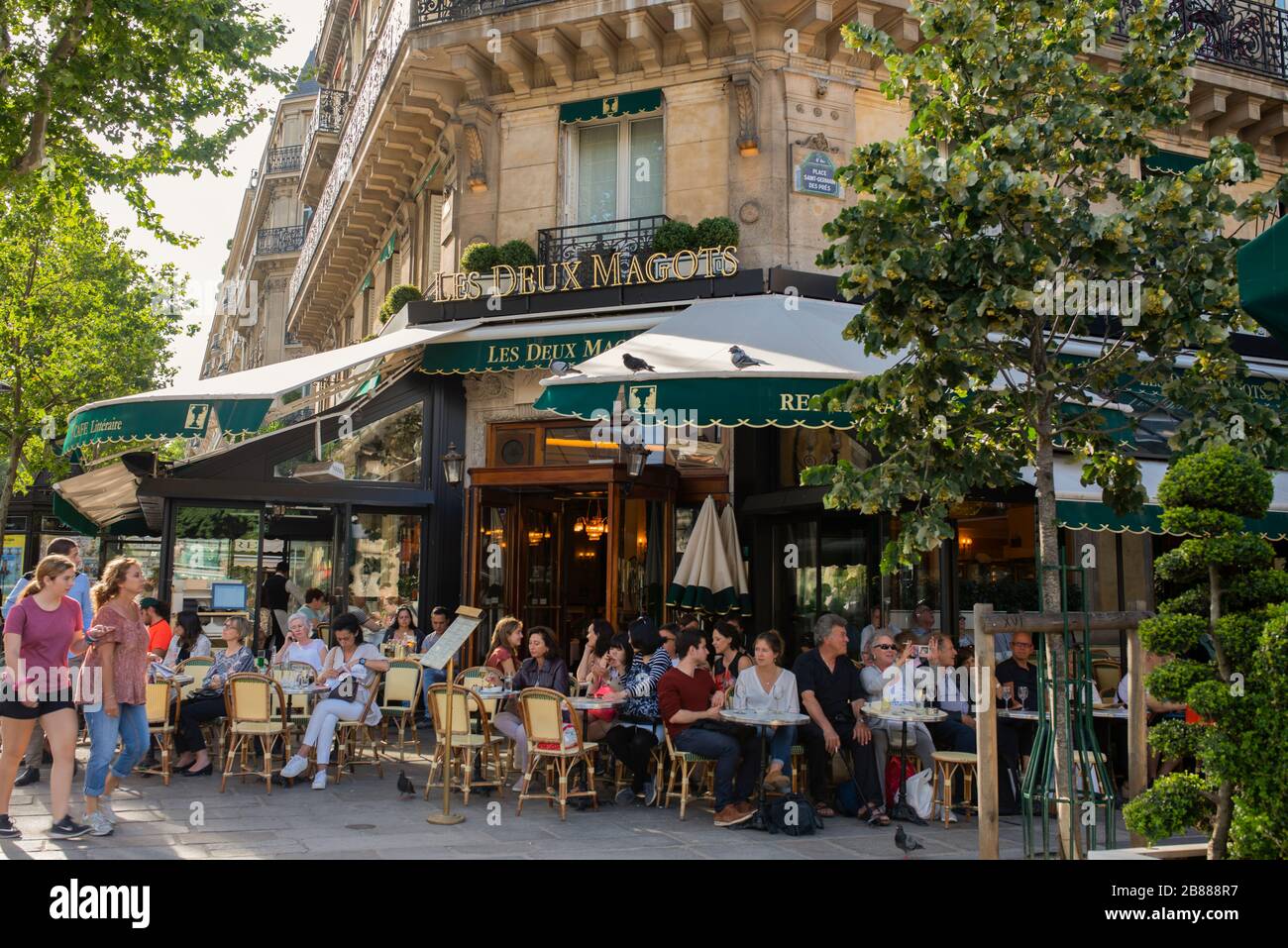 The famous cafe Les Deux magots located in parisian Saint Germain des Pres area;  sunny summer day in Paris. People sitting in the french cafe outside Stock Photo
