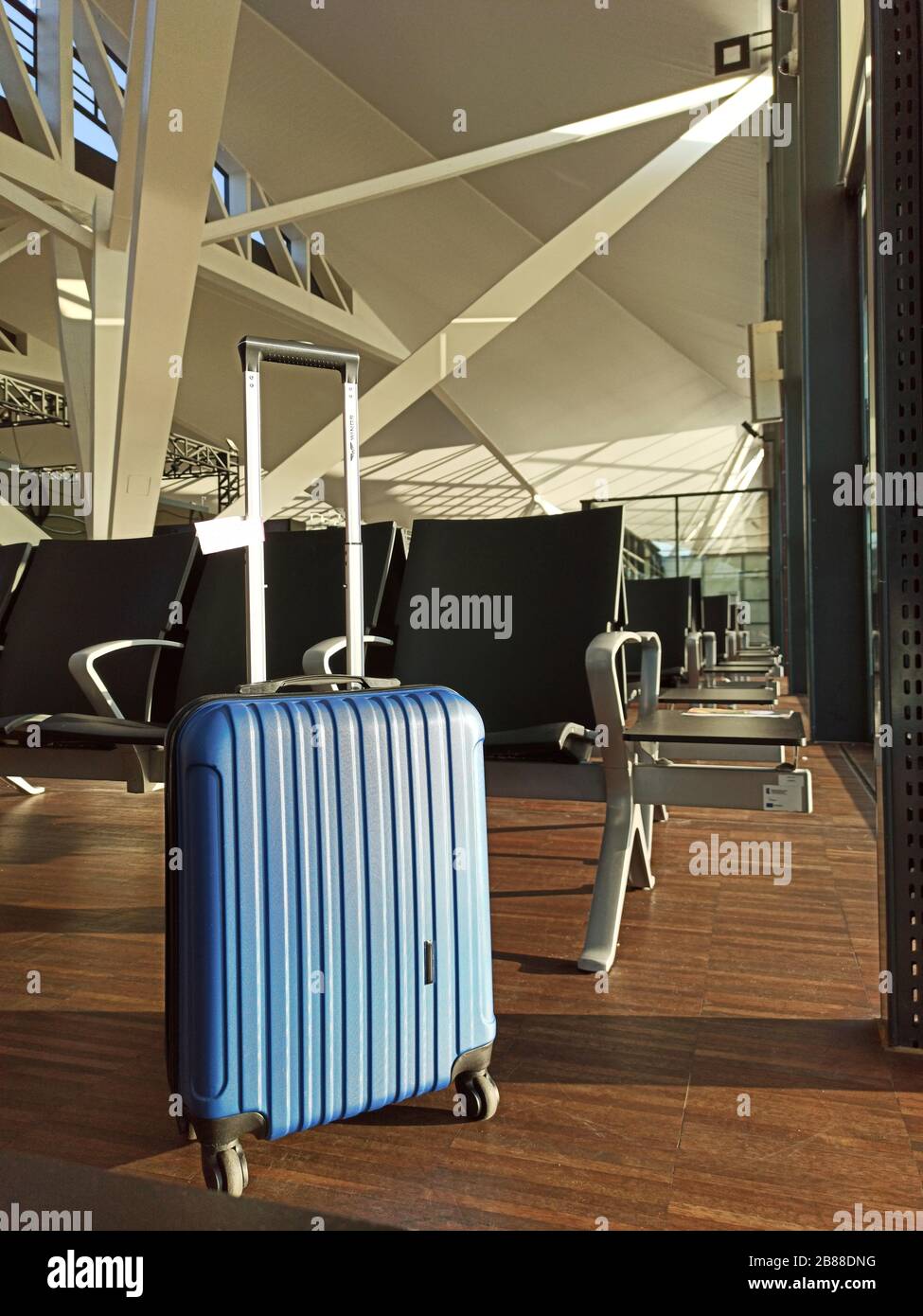 Blue suitcase in an empty airport. Waiting area Flight delay cancellation. Travel and vacation concept. Coronavirus COVID19 quarantine Stock Photo