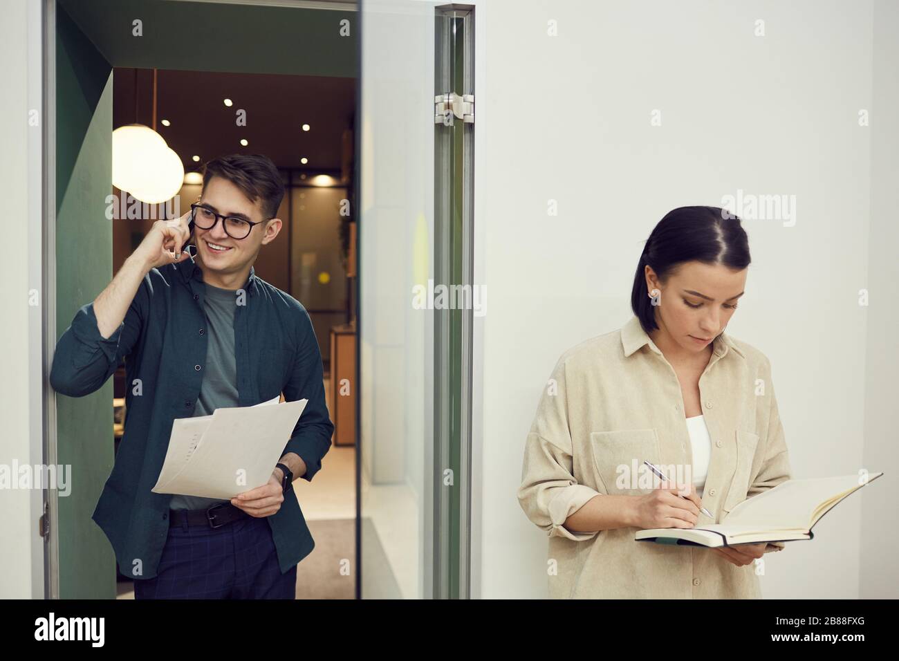 Two office worker busy with their work they talking on the phone and working with documents at office Stock Photo