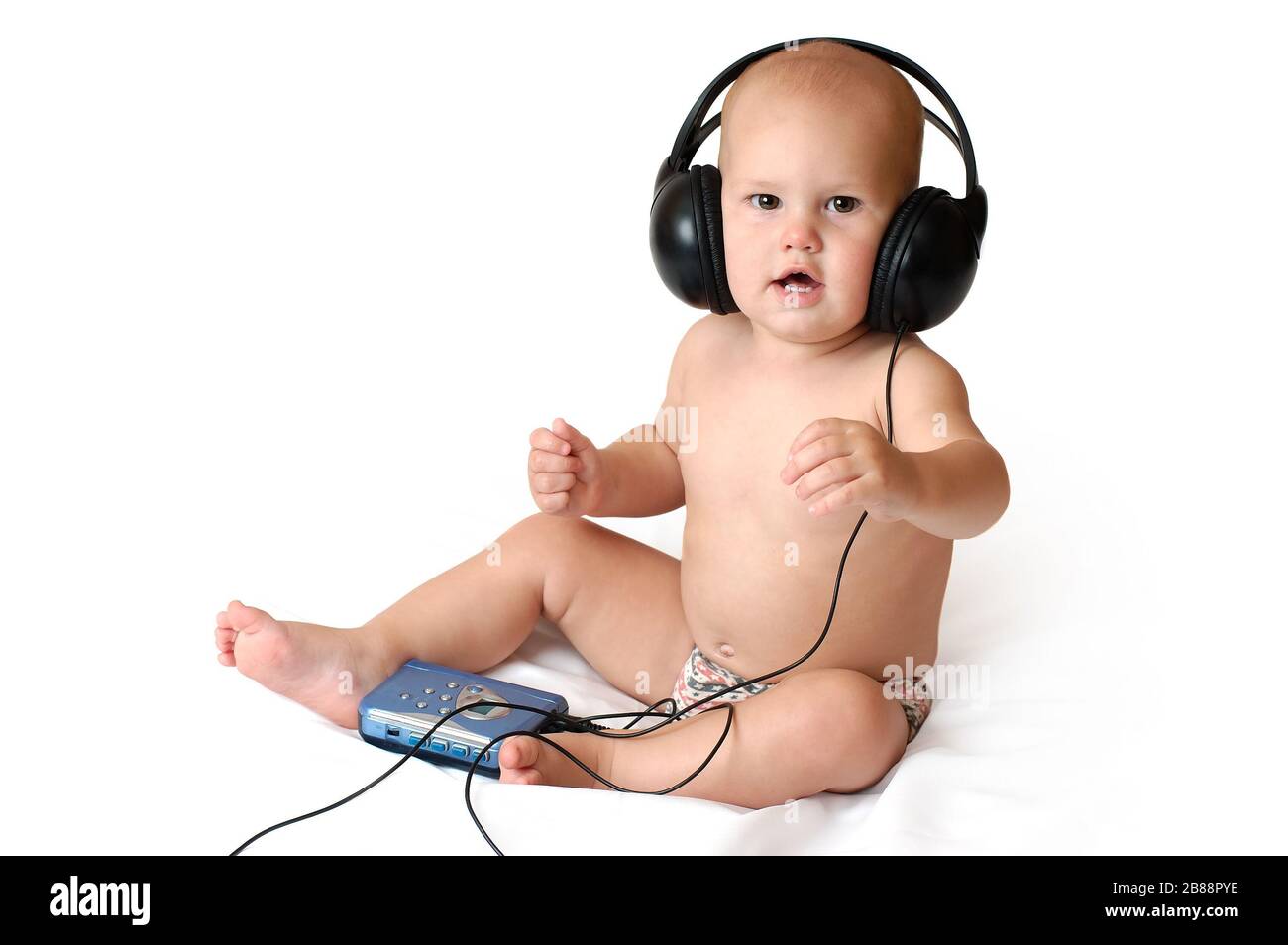 Little one year old boy listens to walkman music in big headphones and smiles on an isolated white background Stock Photo
