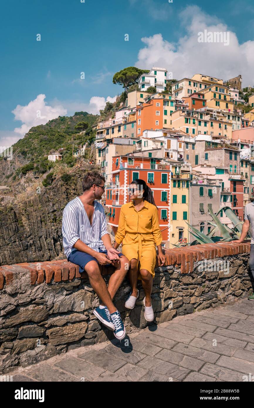 View of Riomaggiore one of Cinque Terre in the province of La Spezia, Italy, happy young couple picnic in the mountain with a look over the ocean Stock Photo