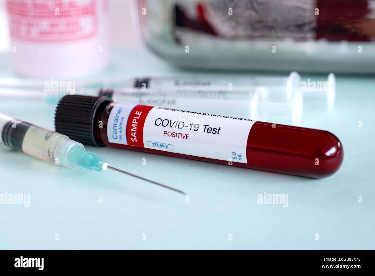 Testing for presence of coronavirus. Syringe with vaccine and tube containing a blood sample that has tested positive for Stock Photo
