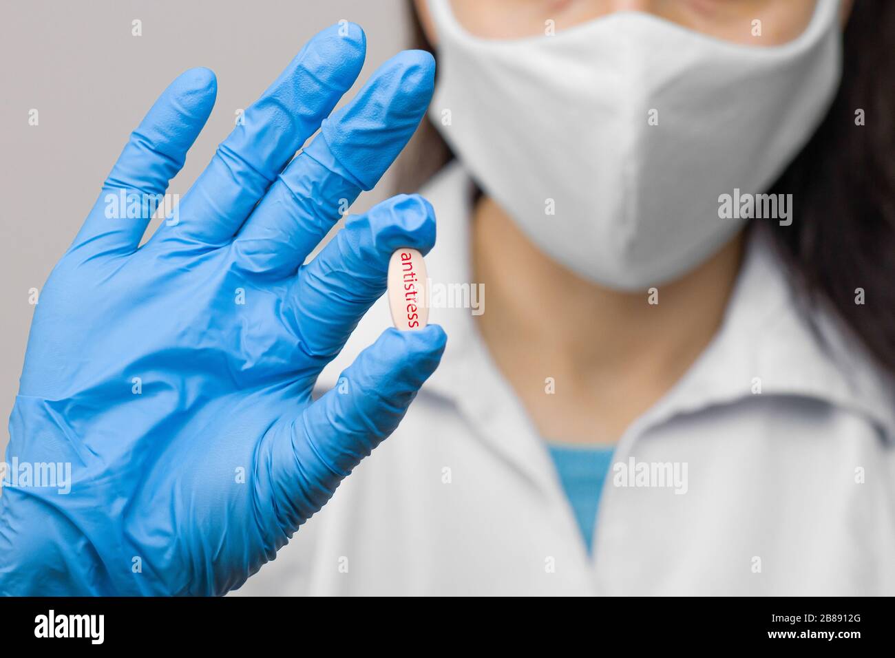 Antistress pill in hand in blue gloves. Female is holding a medicine. Drugs against coronavirus,2019-nCoV, SARS-nCov, COVID-2019 outbreaking. Stock Photo