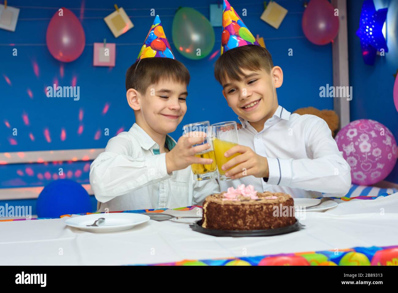Two brothers banging glasses of juice at a birthday party Stock Photo