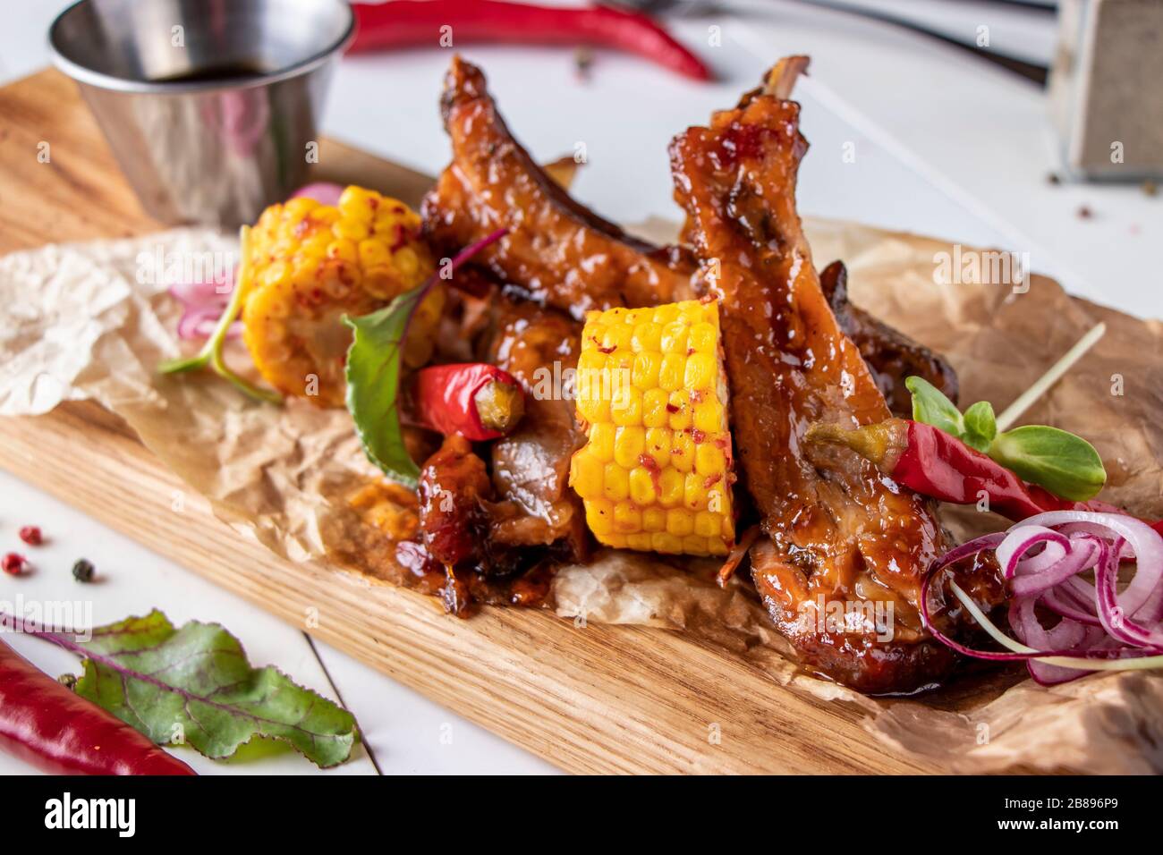Glazed pork ribs baked in soy sauce served with corn on a wooden board, horizontal format Stock Photo